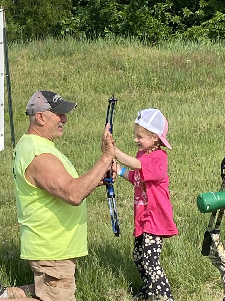 Kicking Bear founder Ray Howell showing kid a bow